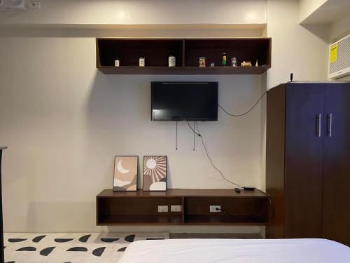 um quarto com uma cama e uma televisão na parede em Condo in Bacolod AMAIA steps em Bacolod