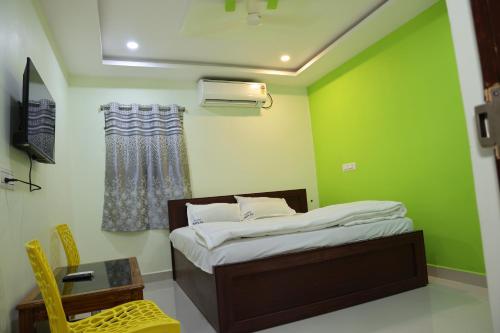 um quarto com uma cama e uma parede verde em Royal Stay Inn em Simhāchalam