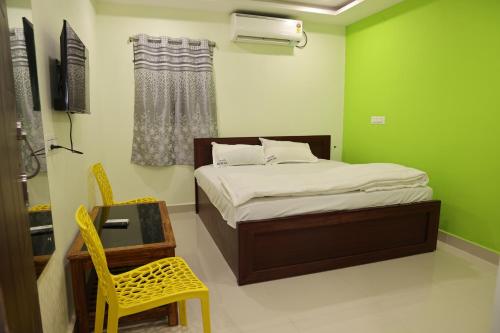um quarto verde com uma cama e uma cadeira amarela em Royal Stay Inn em Simhāchalam