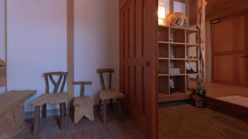 a room with two wooden chairs and a book shelf at Woody Island in Hakuba