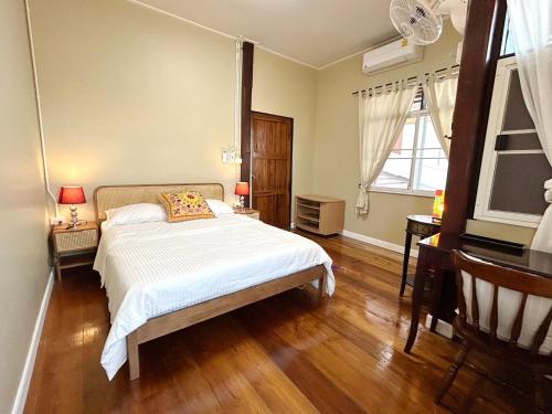 1 dormitorio con cama, suelo de madera y ventana en บ้านมาดามกรีน Baan Madamn Green Nan, en Nan