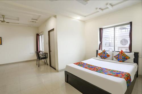 Habitación blanca con cama y silla. en FabHotel HRG Destiny, en Nagpur