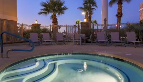 a swimming pool at night with chairs and palm trees at Holiday Inn Express Las Vegas Stadium Area by IHG in Las Vegas