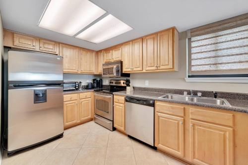 una cocina con armarios de madera y electrodomésticos de acero inoxidable en Wind Drift 307S, en Orange Beach