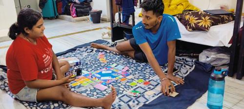 dos personas sentadas en el suelo jugando un juego de mesa en KyGo Hostels en Hyderabad