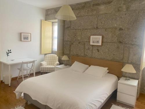 ein Schlafzimmer mit einem weißen Bett und einer Steinmauer in der Unterkunft Casa das Mouras- Rio de Moinhos in Rio de Moinhos
