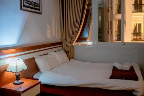 Cama en habitación con lámpara y ventana en Ngọc Châu Hotel Đà Lạt, en Da Lat