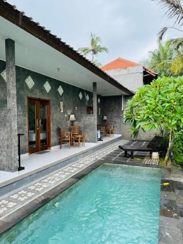 a villa with a swimming pool in front of a house at Biya Lumba in Candidasa