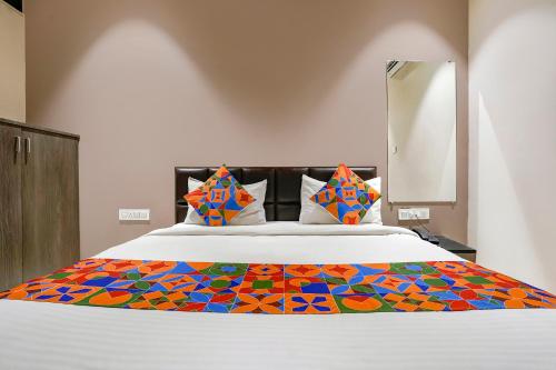 a bed with a colorful blanket on top of it at FabExpress Ospite in Surat