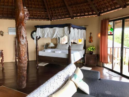 a bedroom with a canopy bed and a couch at Camotes Cay Hideaway in San Francisco