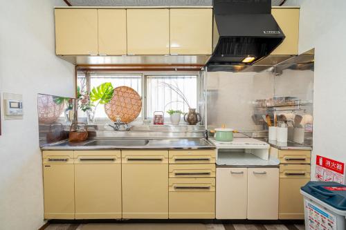 una cocina con armarios amarillos y fregadero en Jujo house Shinjuku direct with 4BR, en Tokio