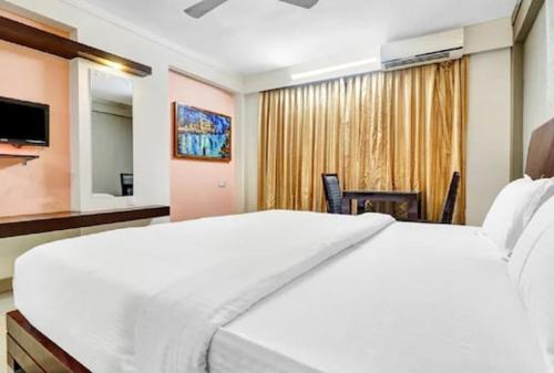 ein Schlafzimmer mit einem großen weißen Bett und einem TV in der Unterkunft AEC Travel and Leisure Solution Pvt Ltd in Alappuzha