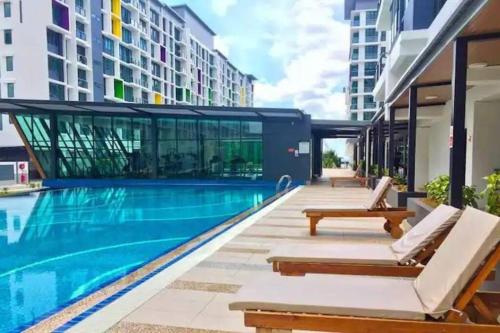basen z 2 leżakami obok budynku w obiekcie Vivacity Megamall Jazz Suite Kuching 8pax 3BR #Joyoustayz w mieście Kuching