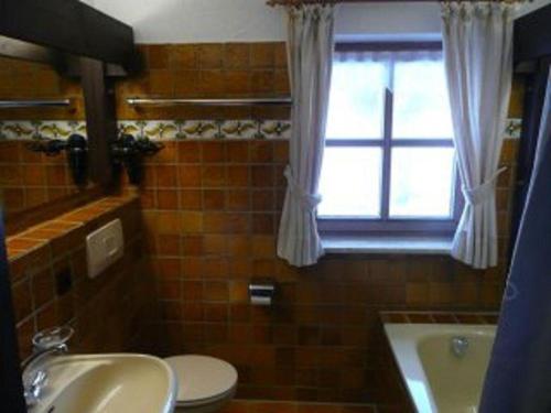 uma casa de banho com um lavatório, um WC e uma janela. em FeWo-in-Unterwoessen-Chiemgau-Oberbayern em Unterwössen