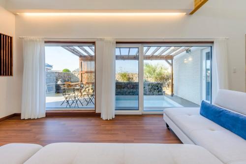 a living room with a white couch and sliding glass doors at Tov & Kara in Jeju