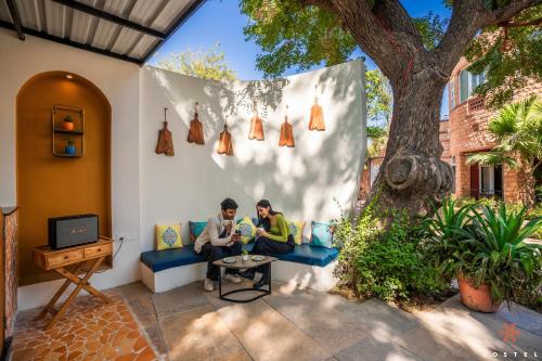 two men sitting on a couch under a tree at Zostel Jodhpur (Ratanada) in Jodhpur