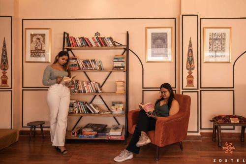 two women standing in a living room looking at their cell phones at Zostel Jodhpur (Ratanada) in Jodhpur