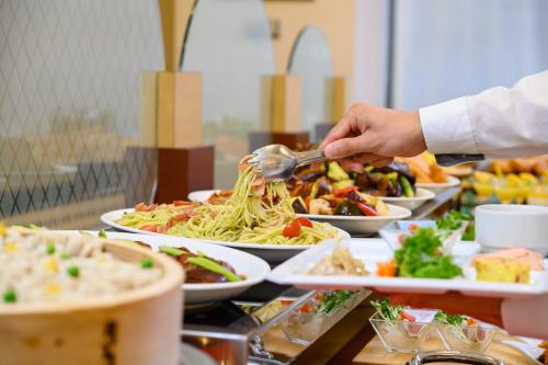 a person serving food on a buffet line with plates of food at Hotel Green Park Tsu in Tsu