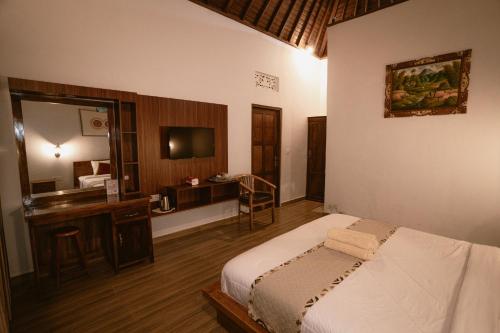 a bedroom with a bed and a desk and a television at The Green Ponci Bedugul in Baturiti