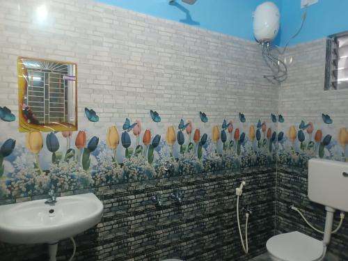 uma casa de banho com um lavatório e um mural de flores na parede em SURYA VILLA GUEST HOUSE em Tajpur
