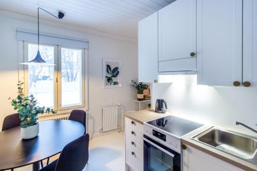a kitchen with white cabinets and a table and a sink at Villa Aurinko Studio Apartment in Hanko in Hanko