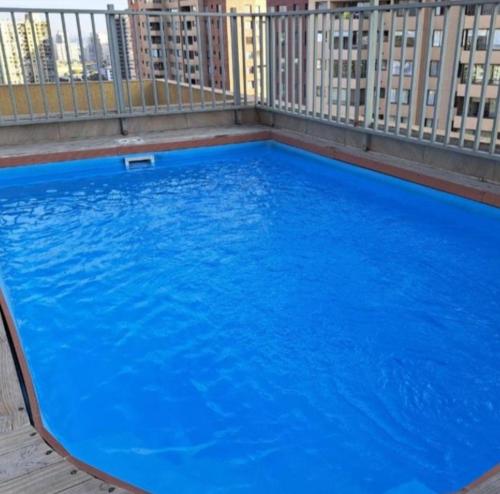 a large blue swimming pool on top of a building at Apartamento tipo estudio acogedor entre metro católica y baquedanono in Santiago