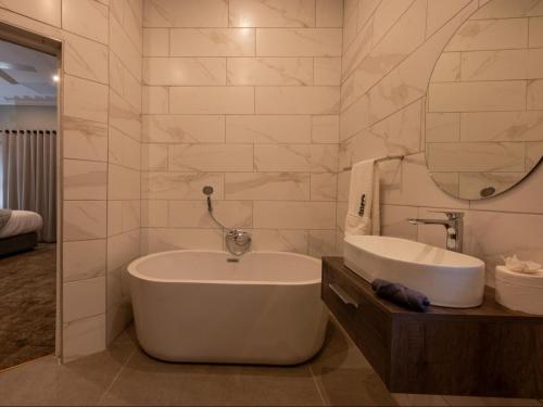 a bathroom with a tub and a sink and a mirror at Familia Guesthouse in Groblersdal