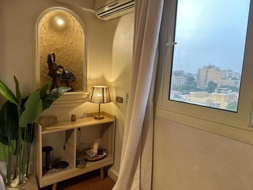 een kamer met een raam en een tafel met een lamp bij The Paradise Luxury Apartment in Caïro