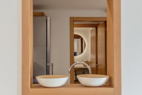Duas tigelas brancas numa prateleira de madeira na casa de banho em Sa Perdiu 7 em Cala Santandria