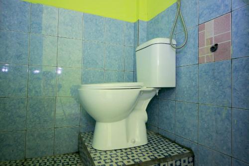 a white toilet in a blue tiled bathroom at OYO 2585 Sherren Guest House in Lubuklinggau