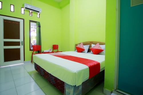 a bedroom with a bed with red and green walls at OYO 2585 Sherren Guest House in Lubuklinggau