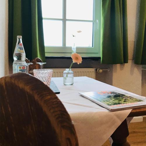 a table with a flower in a vase on it at Gästehaus Hotel Maria Theresia in Schliersee