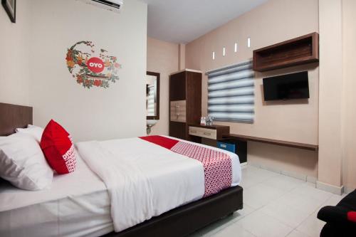 a bedroom with a bed with red pillows and a tv at OYO 725 My Arm Home & Stay in Medan