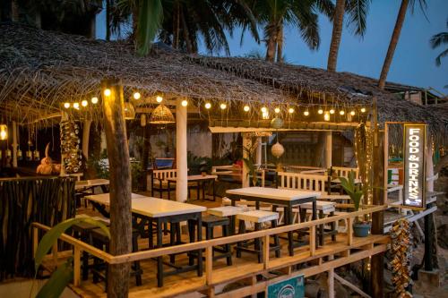 a restaurant with tables and lights and palm trees at Oynise Beach Cabin in Galle