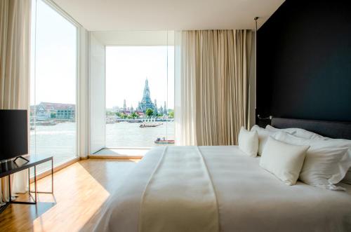 a large white bed in a room with a large window at Sala Rattanakosin Bangkok in Bangkok