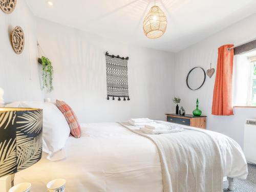 1 Bed in Crackington Haven HAWTH في Saint Gennys: غرفة نوم بيضاء مع سرير وستائر برتقالية