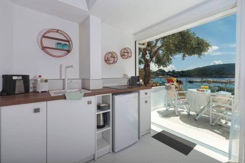 a kitchen with white cabinets and a large window at Napoleon On The Beach in Paleokastritsa