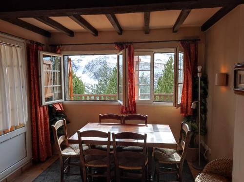 a dining room with a table and chairs and windows at Urb. Bugaboos - Sierra Nevada in Monachil