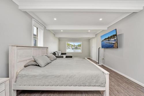 a white bedroom with a large bed and a couch at Balmoral Waterfront Escape at Lake Macquarie in Balmoral
