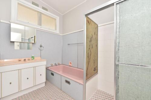 y baño con bañera rosa y ducha. en Waterfront Bliss at Balmoral Lake Macquarie, en Balmoral