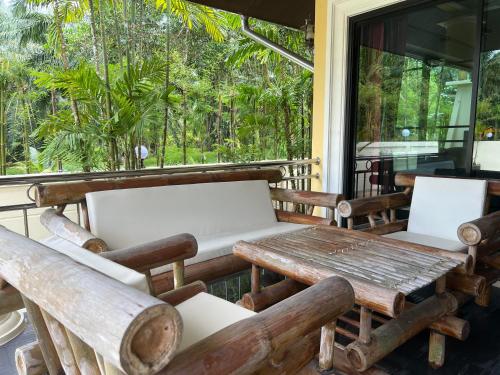 a porch with wooden chairs and a wooden table at Grand Villa Khaolak in Khao Lak