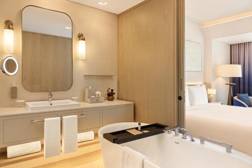 a bathroom with a large mirror and a tub and a bed at Palace Dubai Creek Harbour in Dubai