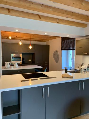 une cuisine ouverte avec des comptoirs blancs et des plafonds en bois dans l'établissement Duplex les Glycines, à Écharvine