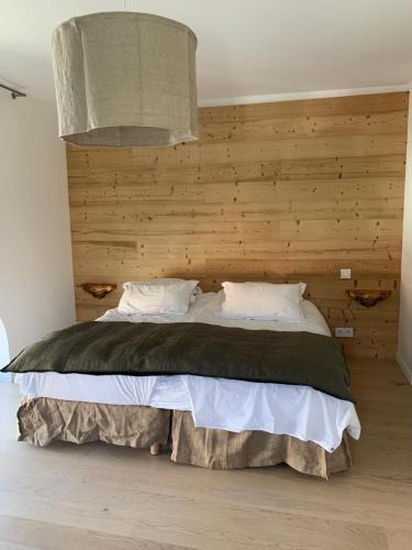 une chambre avec un grand lit avec un mur en bois dans l'établissement Duplex les Glycines, à Écharvine