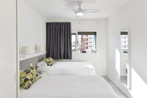 two beds in a white room with a window at Modern Iguazu Apartment in Playa del Ingles