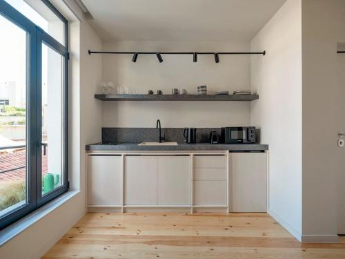 a kitchen with white cabinets and a sink and a window at Hoppersgr- Amazing apt in the heart of Athens - 3 in Athens