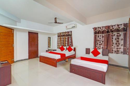 uma sala de estar com 2 camas e almofadas vermelhas em OYO Shree Balaji Residency em Chennai