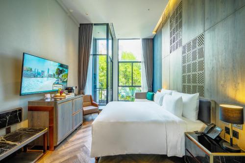 a hotel room with a large bed and a television at Ten Six Hundred, Chao Phraya, Bangkok by Preference, managed by The Ascott Limited in Bangkok