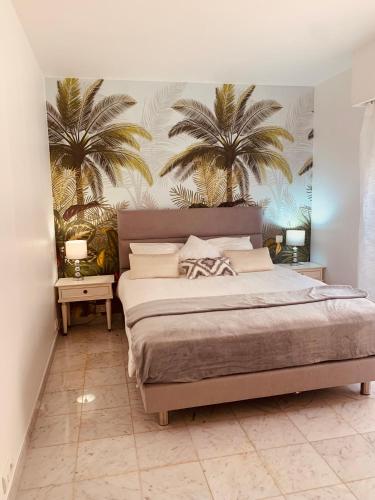 - une chambre avec un lit et deux palmiers sur le mur dans l'établissement Dolce Vita à la Française, à Menton