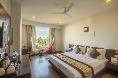 una camera d'albergo con letto e finestra di Vesta Grand Central Udaipur a Udaipur